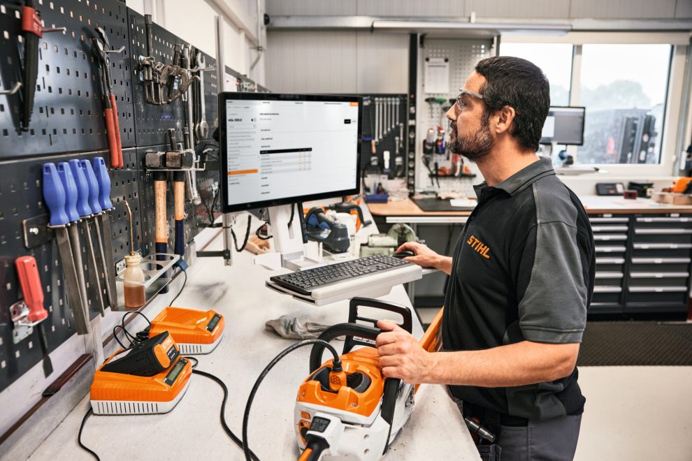 Un homme dans un atelier vérifie les réglages d'une tronçonneuse sur un PC
