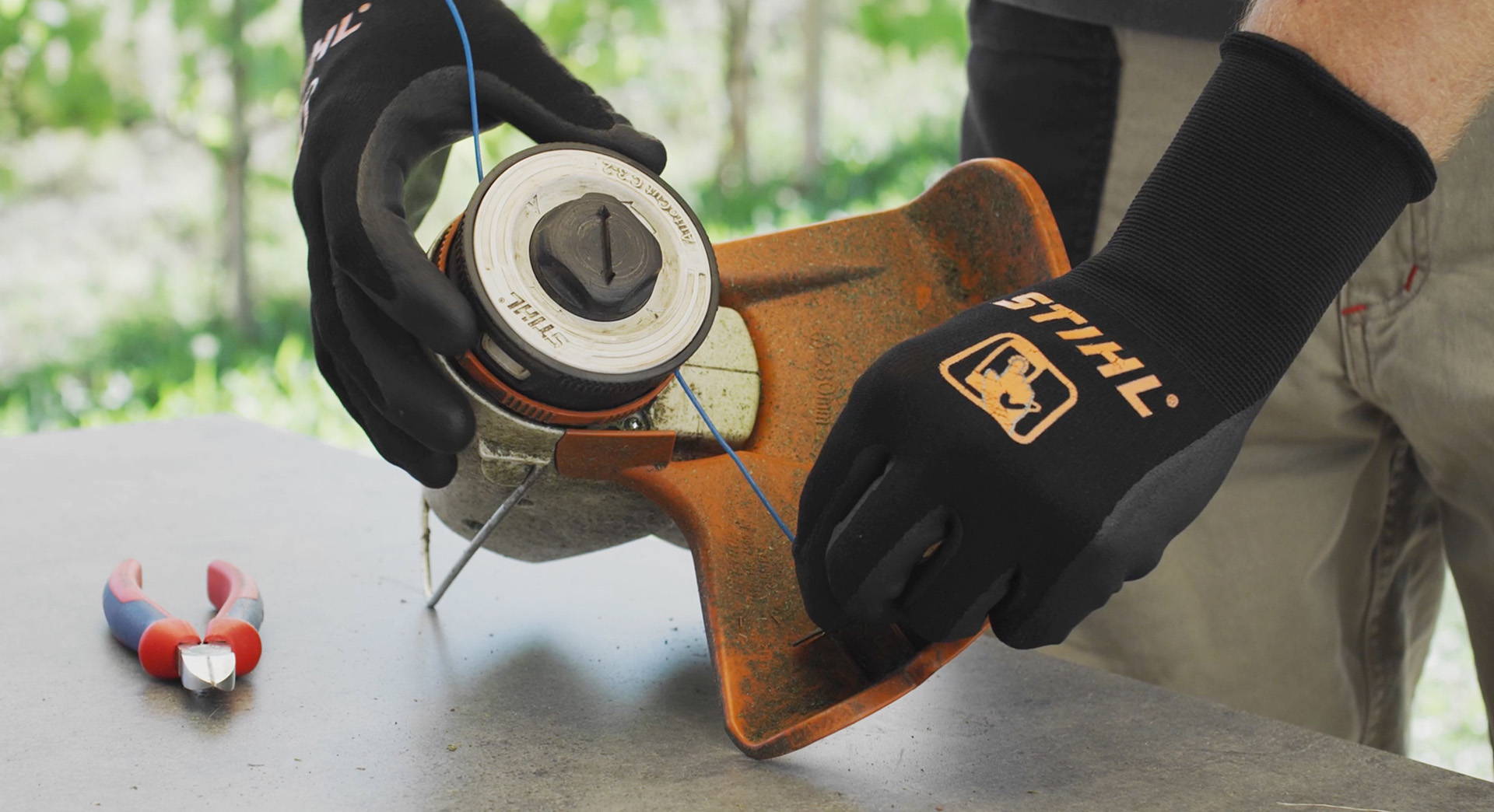Une personne enroule le fil de coupe d’une débroussailleuse à batterie STIHL FSA 57