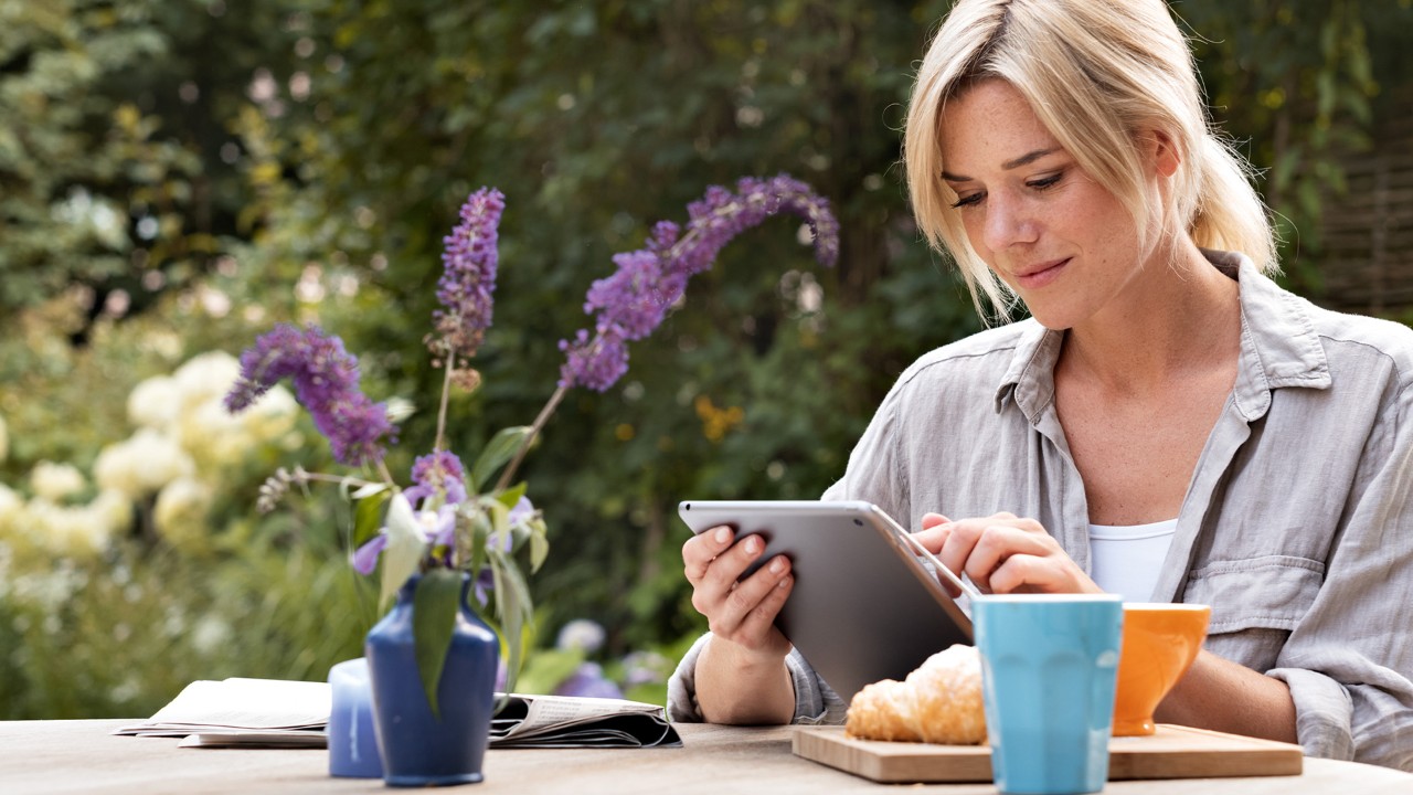 Une femme utilisant une tablette numérique à l’extérieur.