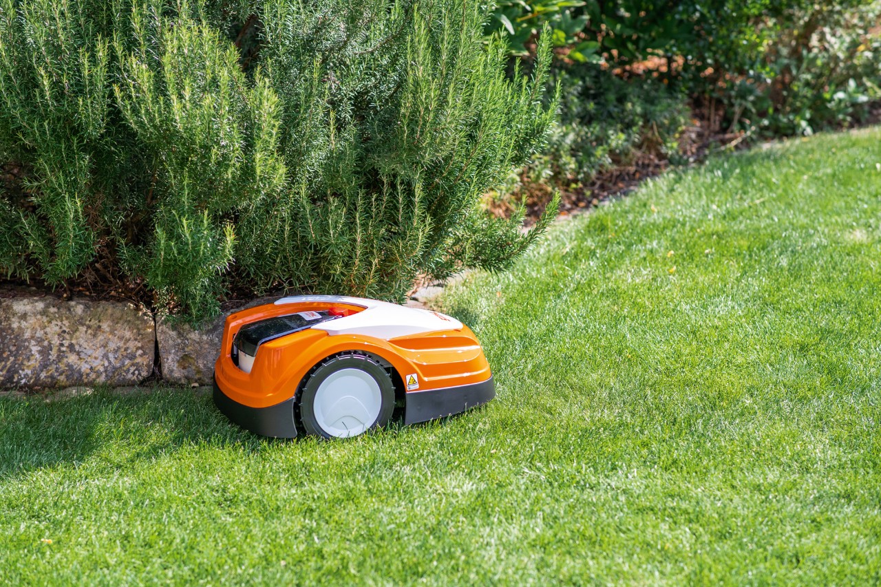 Robot de tonte STIHL iMOW® RMI 422 PC sur une pelouse verte à côté d’une bordure de pierres plates