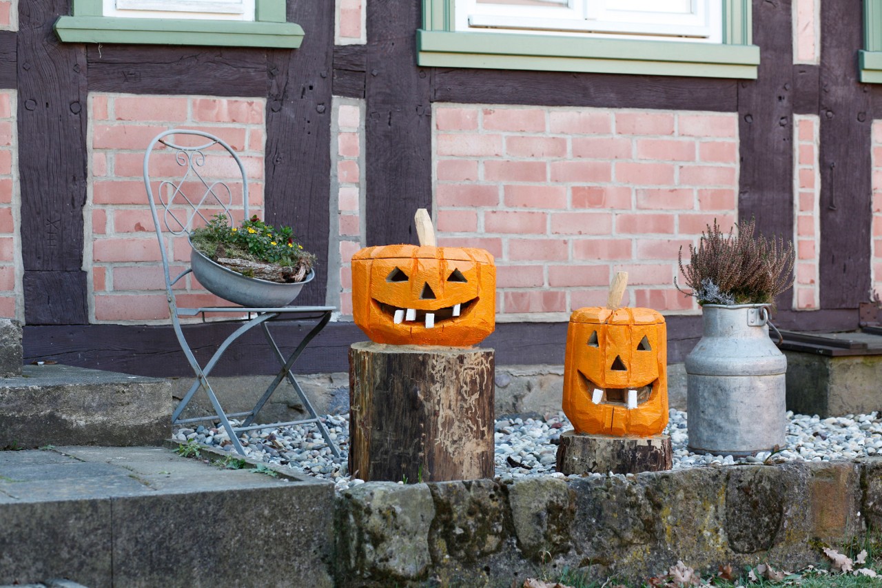 Des citrouilles en bois peintes, sculptées à partir de rondins à l’extérieur d’une maison