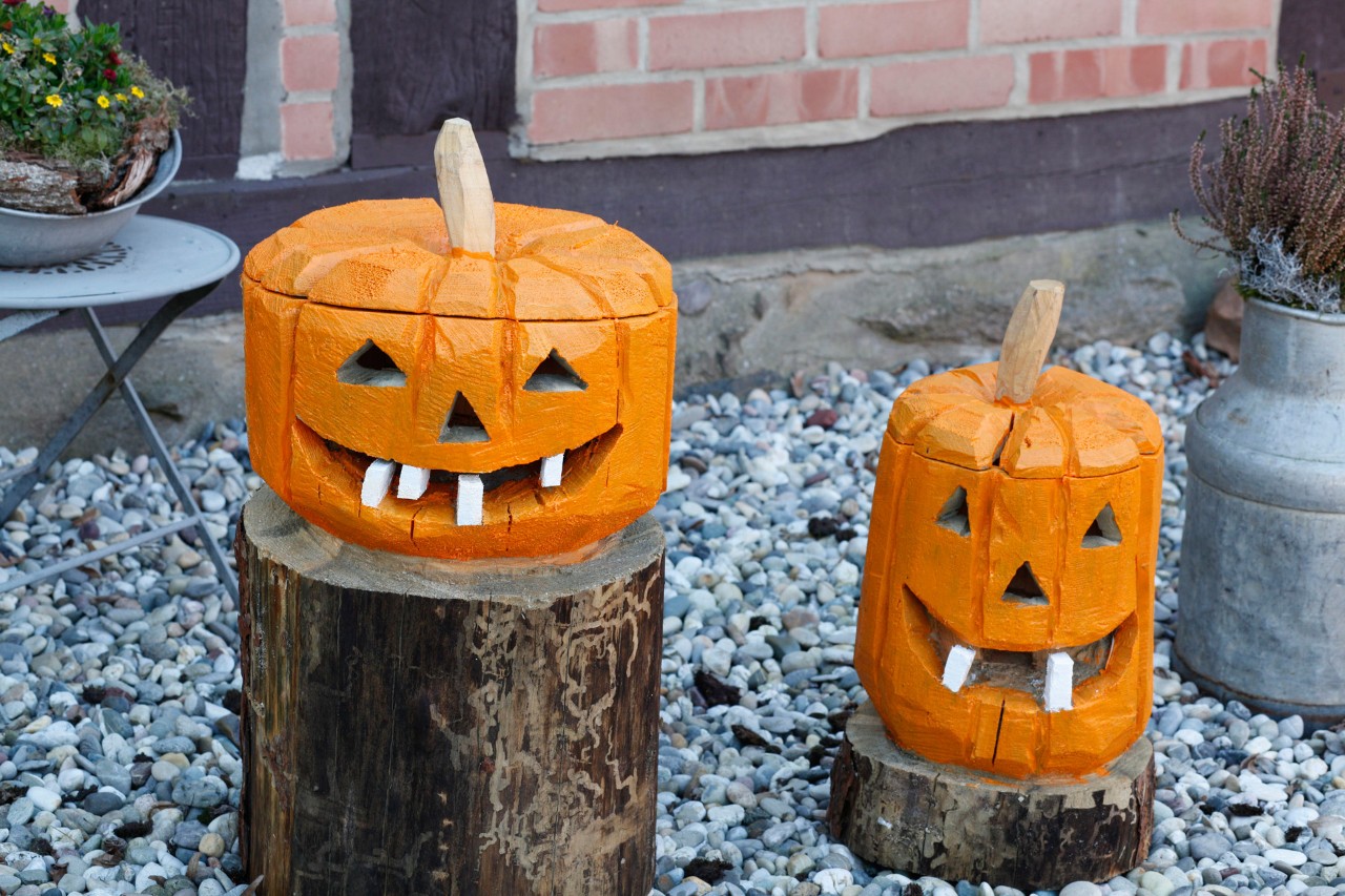 Une paire de citrouille d’Halloween en bois fabriquées à partir de rondins, à l’extérieur d’une maison