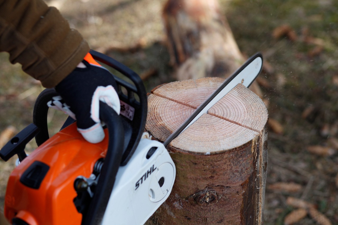 Tronçonneuse thermique STIHL MS 181 découpant deux fentes en croix dans une bûche posée verticalement 