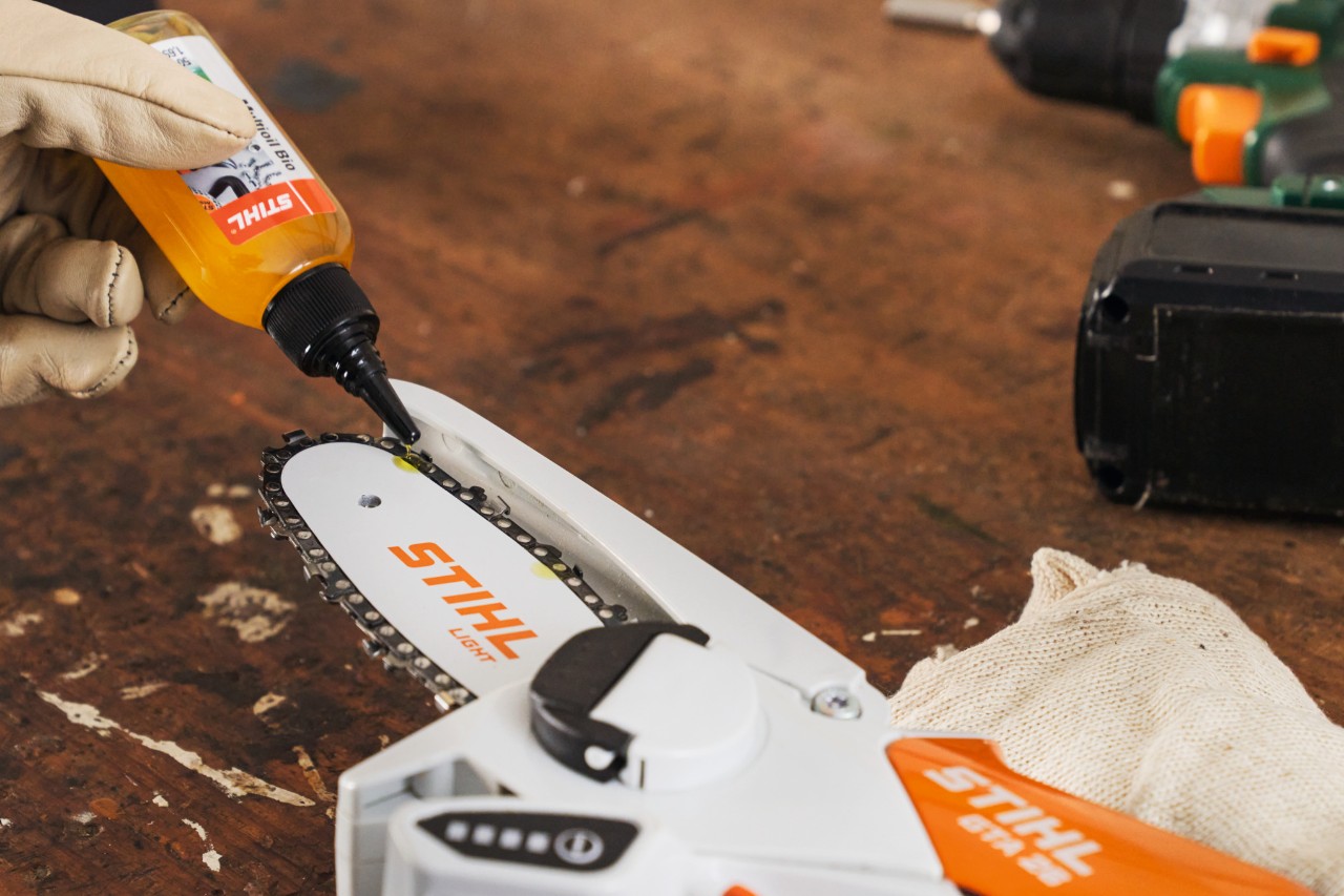 Une personne lubrifie la scie de jardin STIHL GTA 26