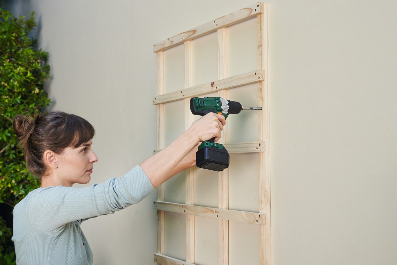 Une femme perce un treillis sur le mur d'une maison