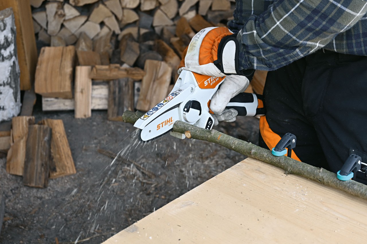 Gros plan sur une personne en train de couper une branche avec la scie de jardin à batterie STIHL GTA 26