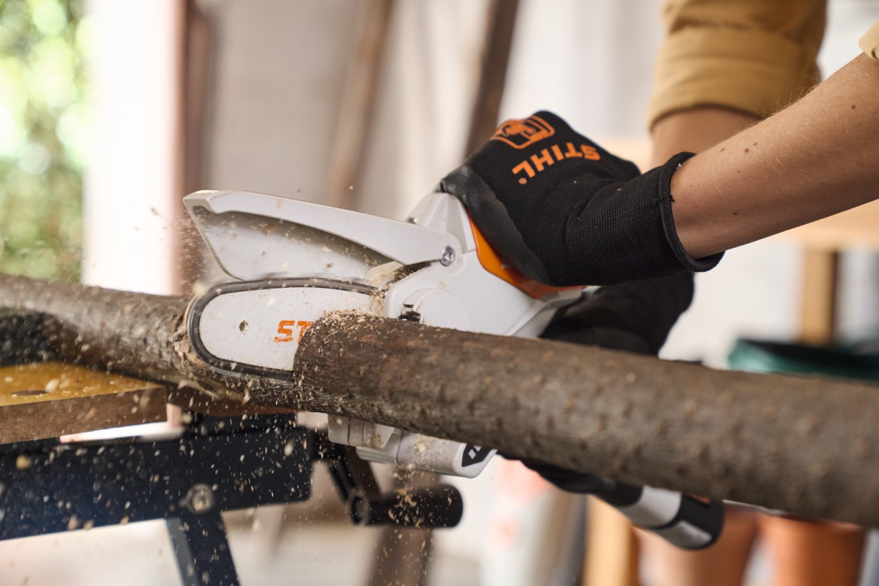 Gros plan sur une personne coupant une branche à la bonne taille avec la scie de jardin STIHL GTA 26
