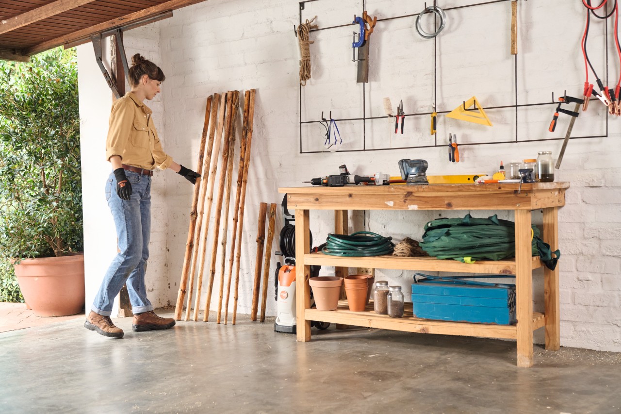 Femme déposant le bois écorcé destiné à la fabrication du portant à vêtements dans un garage pour le faire sécher