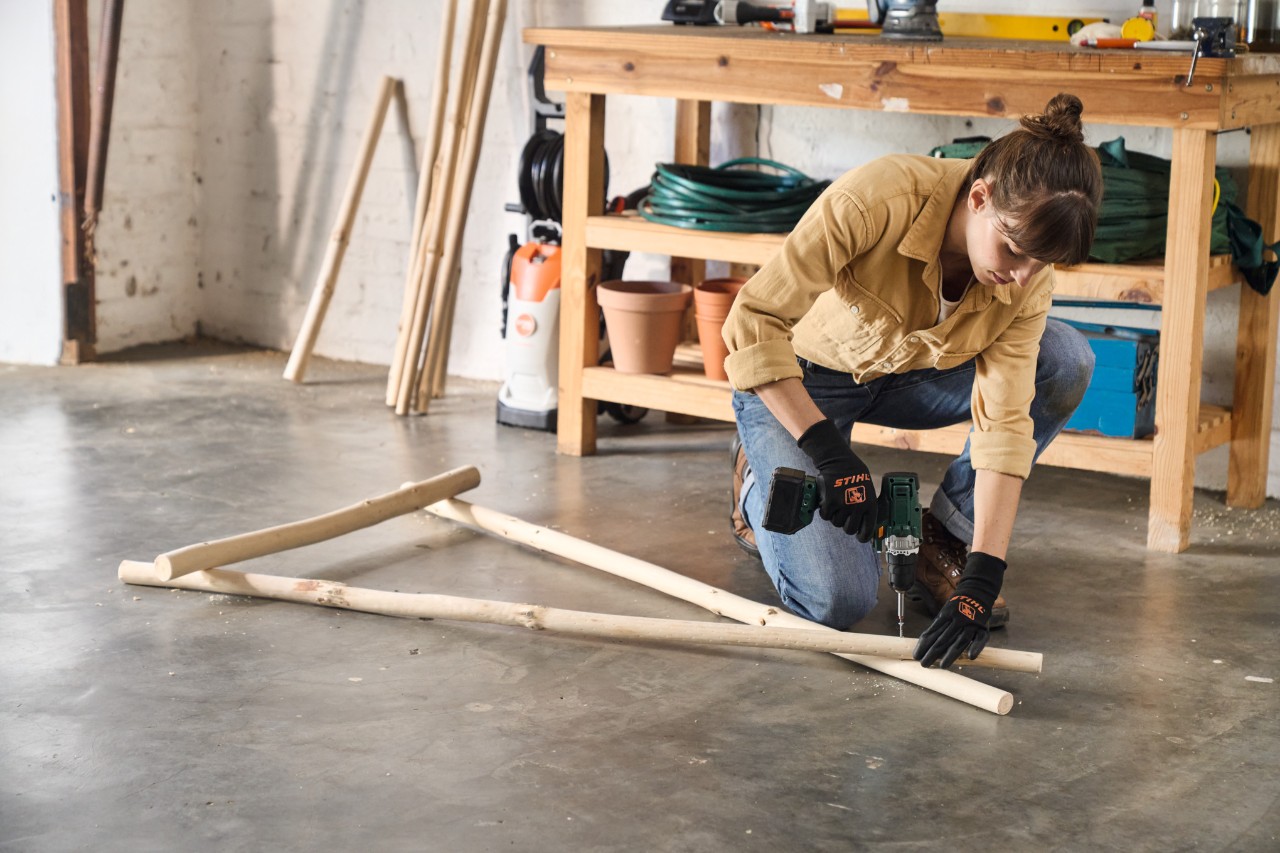 À l’aide d’une visseuse sans fil, une femme visse le bois pour le portant à vêtements qu’elle fabrique elle-même 