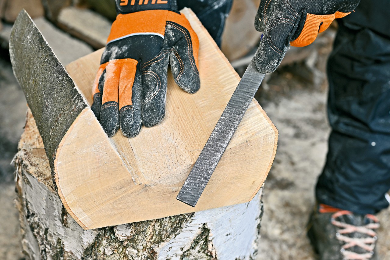 Les bords et les surfaces d’un porte-magazines en bois sont poncés avec une lime métallique
