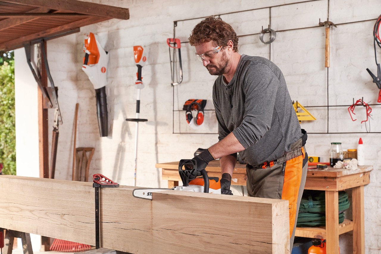 Homme dans l’atelier lors de la découpe d’un madrier en bois avec la tronçonneuse à batterie STIHL MSA 140 C 