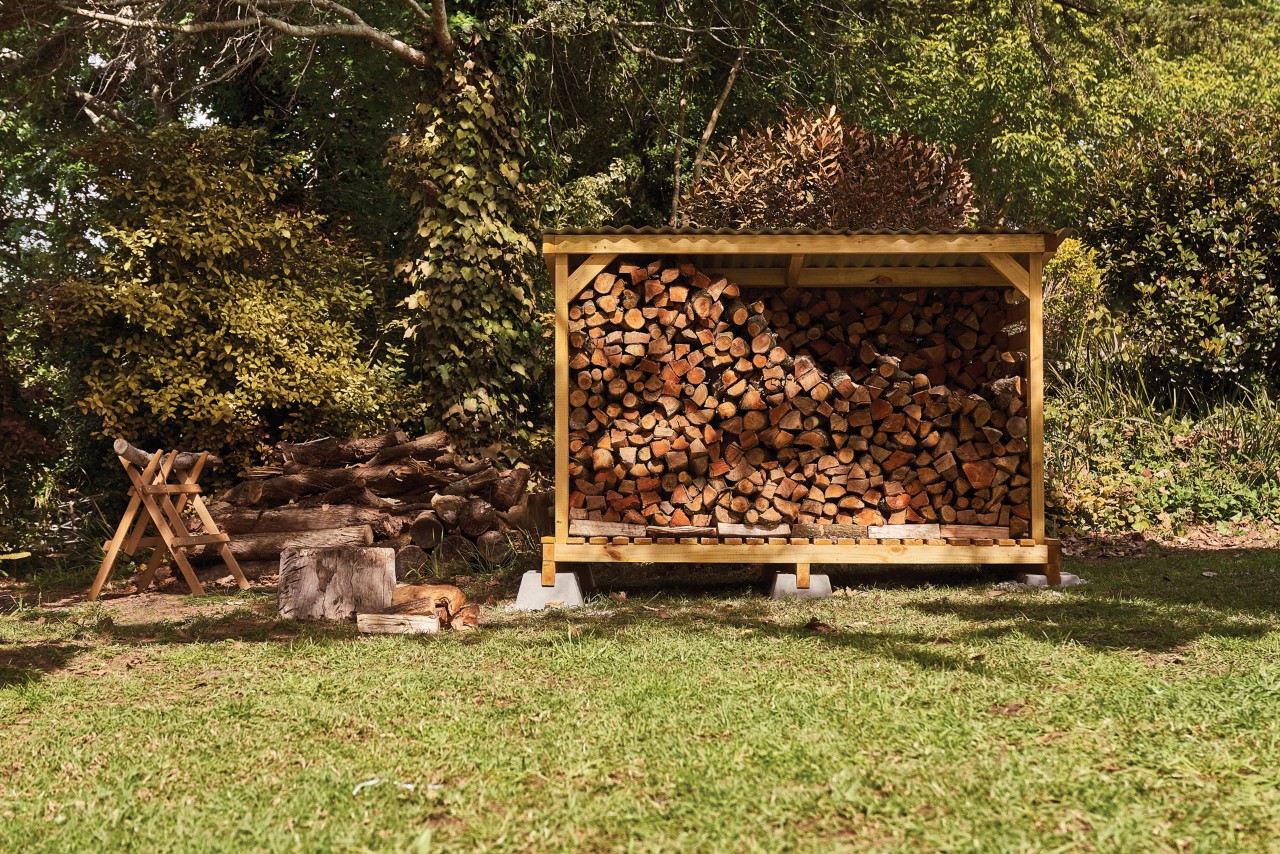 Abri à bois rempli de bûches dans le jardin