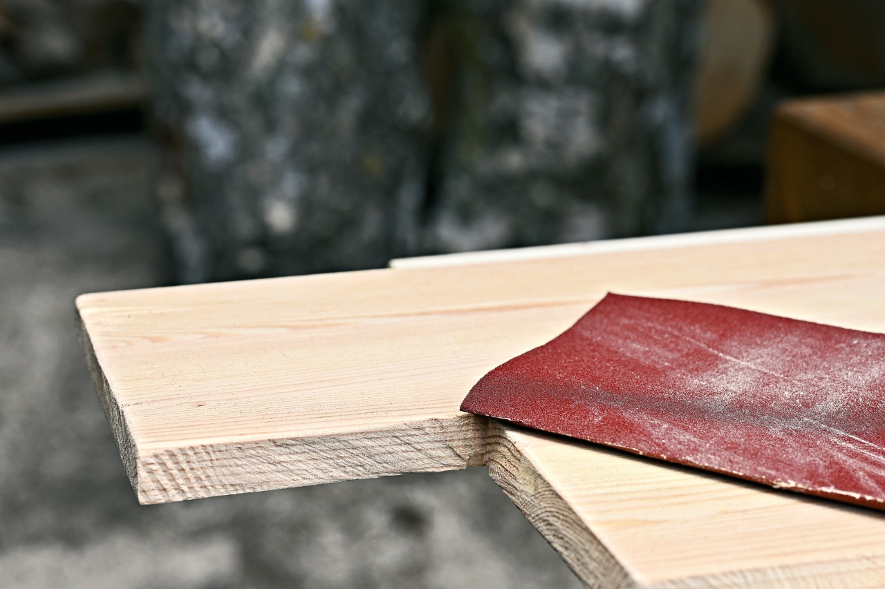 Du papier de verre sur une planche en bois dont un carré a été découpé