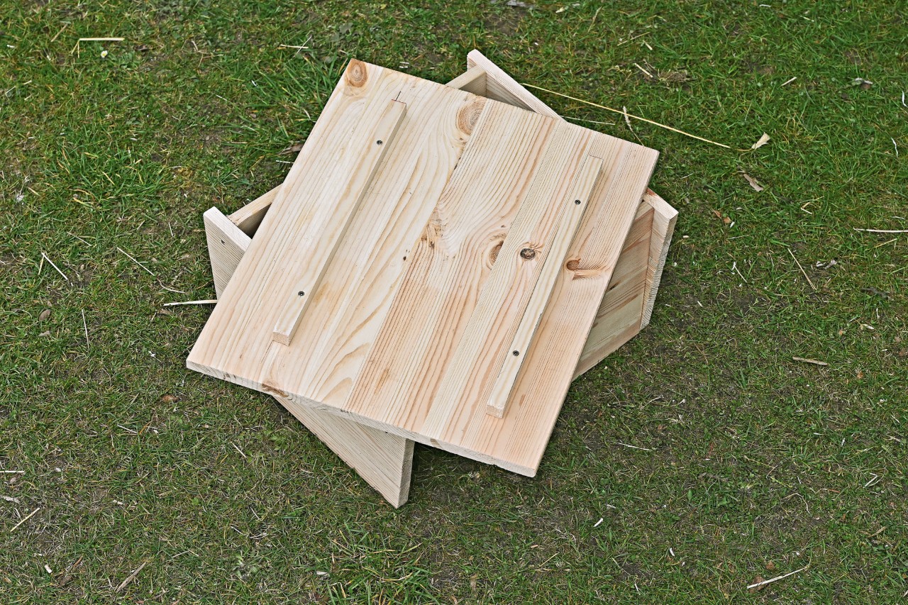 Une planche de toit non fixée avec des tasseaux en bois sur un abri pour hérisson fait maison