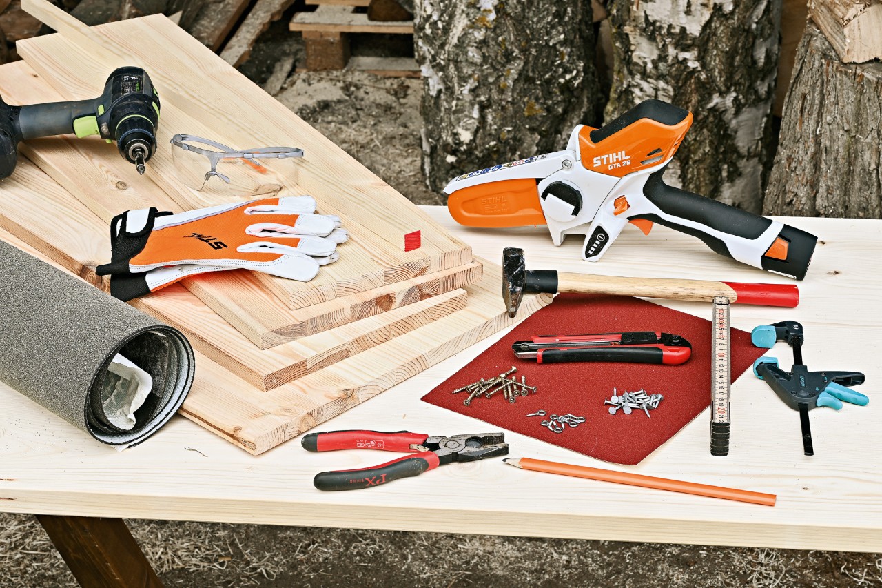 DIY abri pour hérisson : scie de jardin STIHL GTA 26, planches en bois, marteau, clous et quelques autres outils