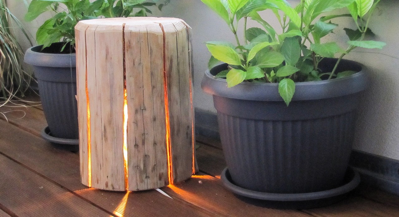 Lampe en bois avec bougie chauffe-plat sur un rebord de fenêtre, à côté de plantes en pot
