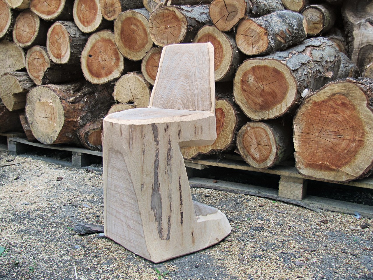 Chaise en bois faite maison devant un tas de bois de chauffage 