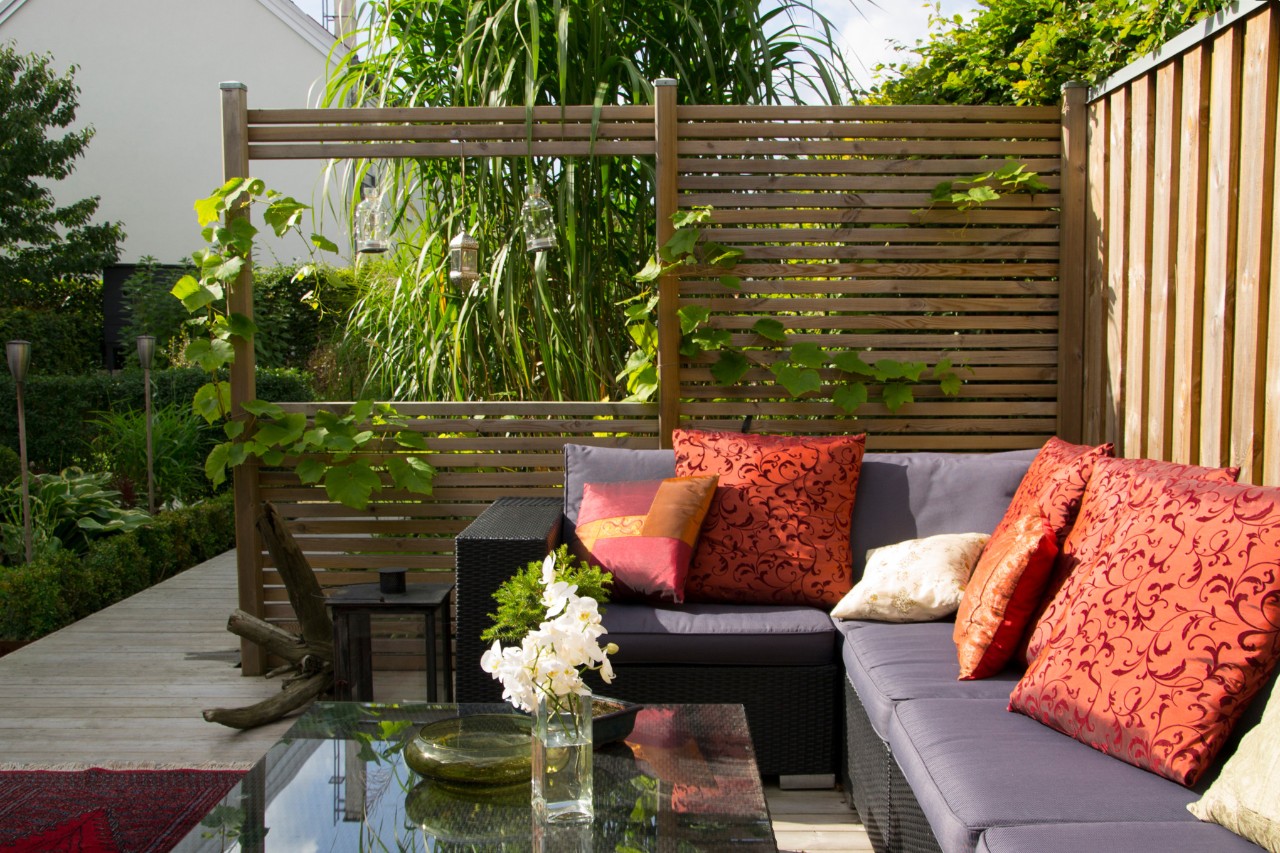 Une terrasse moderne avec un canapé et un brise-vue en bois 