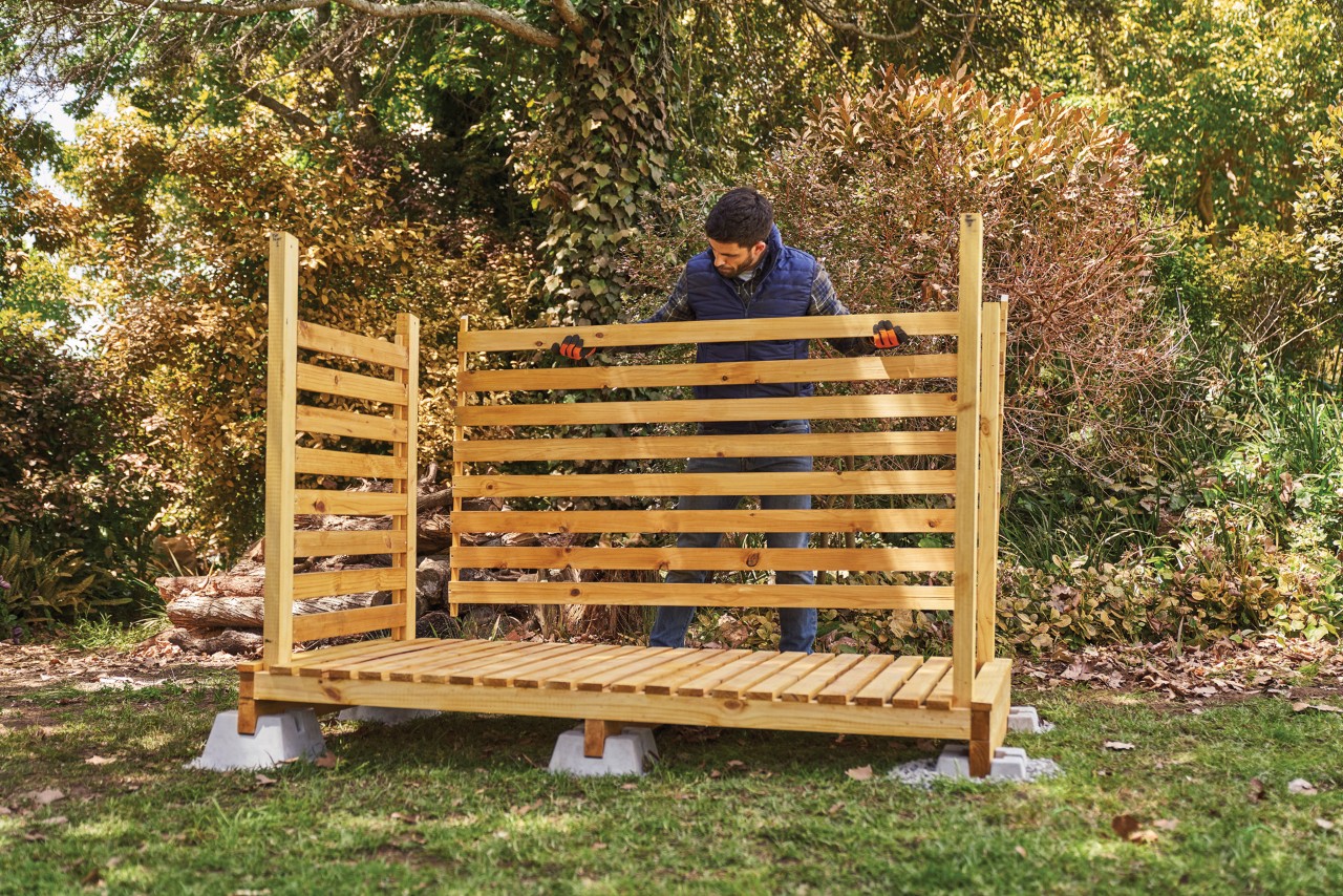 Comment fabriquer un range-bûches : homme installant la paroi arrière d’un range-bûches 