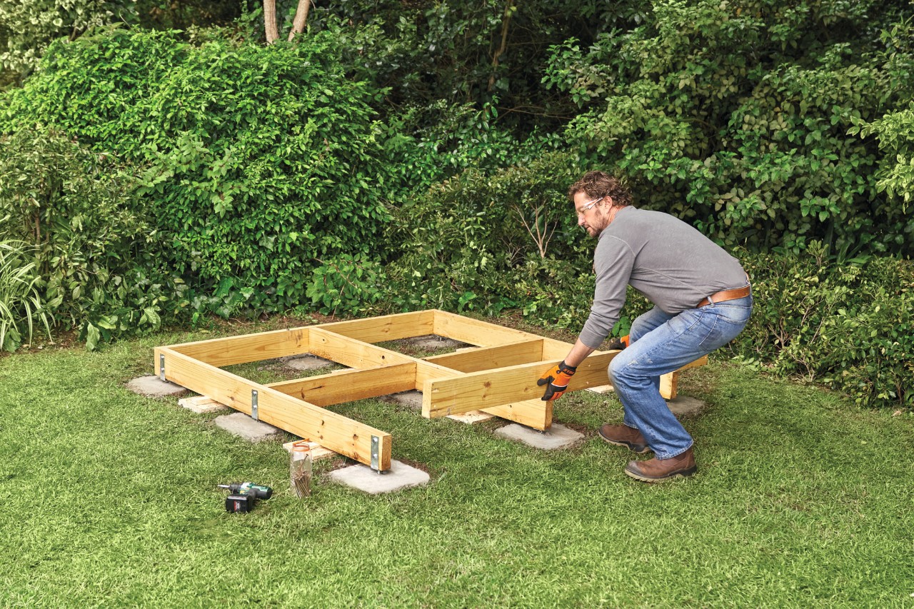 Comment construire un abri de jardin : homme construisant la base en bois d’un abri