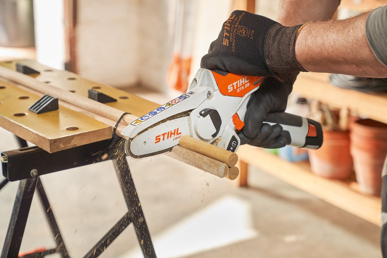 Un homme scie des tiges rondes avec la scie de jardin à batterie STIHL GTA 26