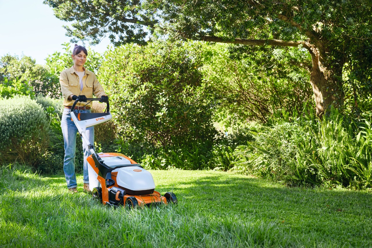 Femme tondant la pelouse avec une tondeuse à gazon à batterie STIHL RMA 448 PV