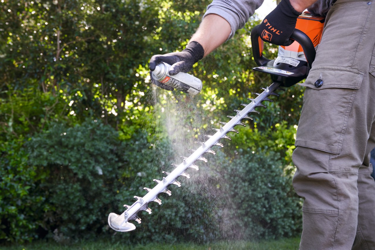 Homme pulvérisant du Multiclean sur le taille-haie à batterie STIHL HSA 60