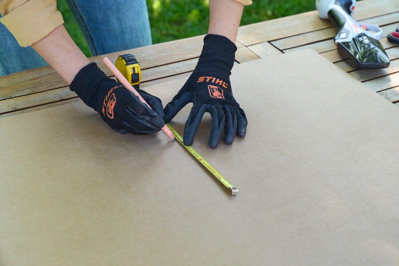 Une femme utilise un mètre ruban pour marquer une longueur sur un carton avec un feutre