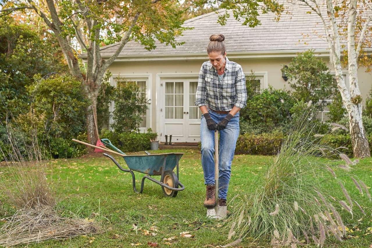 Femme avec des gants de protection STIHL Function SensoTouch travaille avec une bêche dans le jardin pour planter une haie