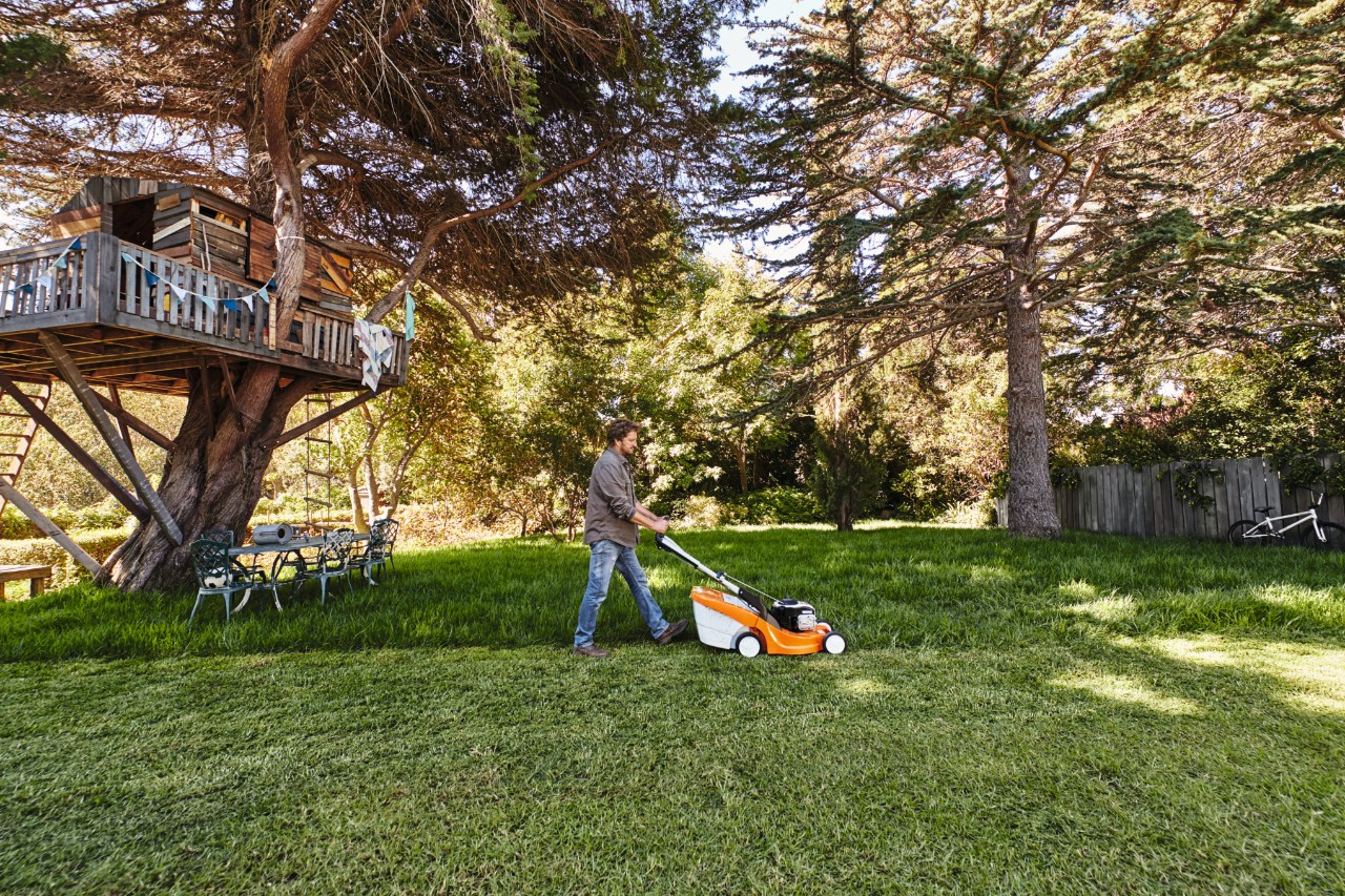 Homme tondant du gazon d’ombre dans un jardin avec pelouse 