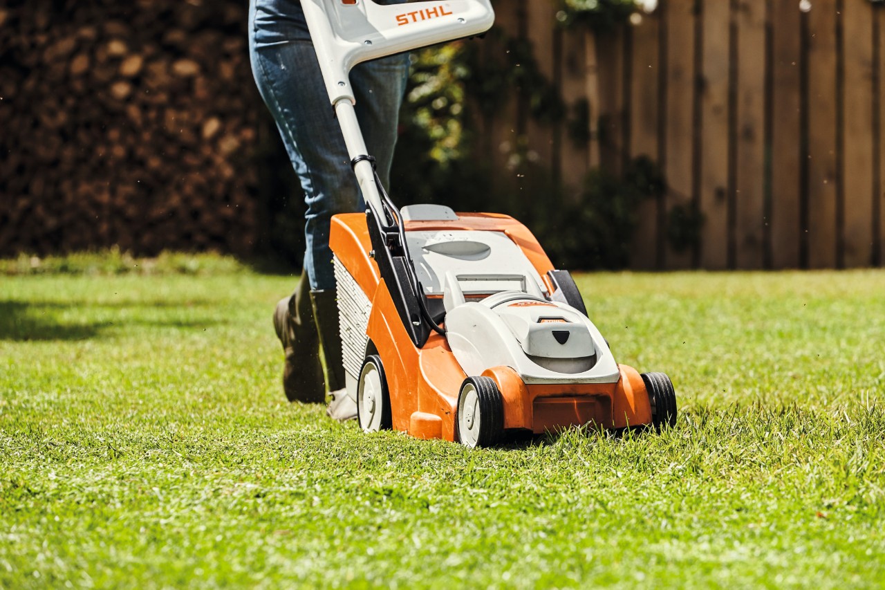 Gros plan sur une personne en train de tondre une pelouse avec une tondeuse STIHL 