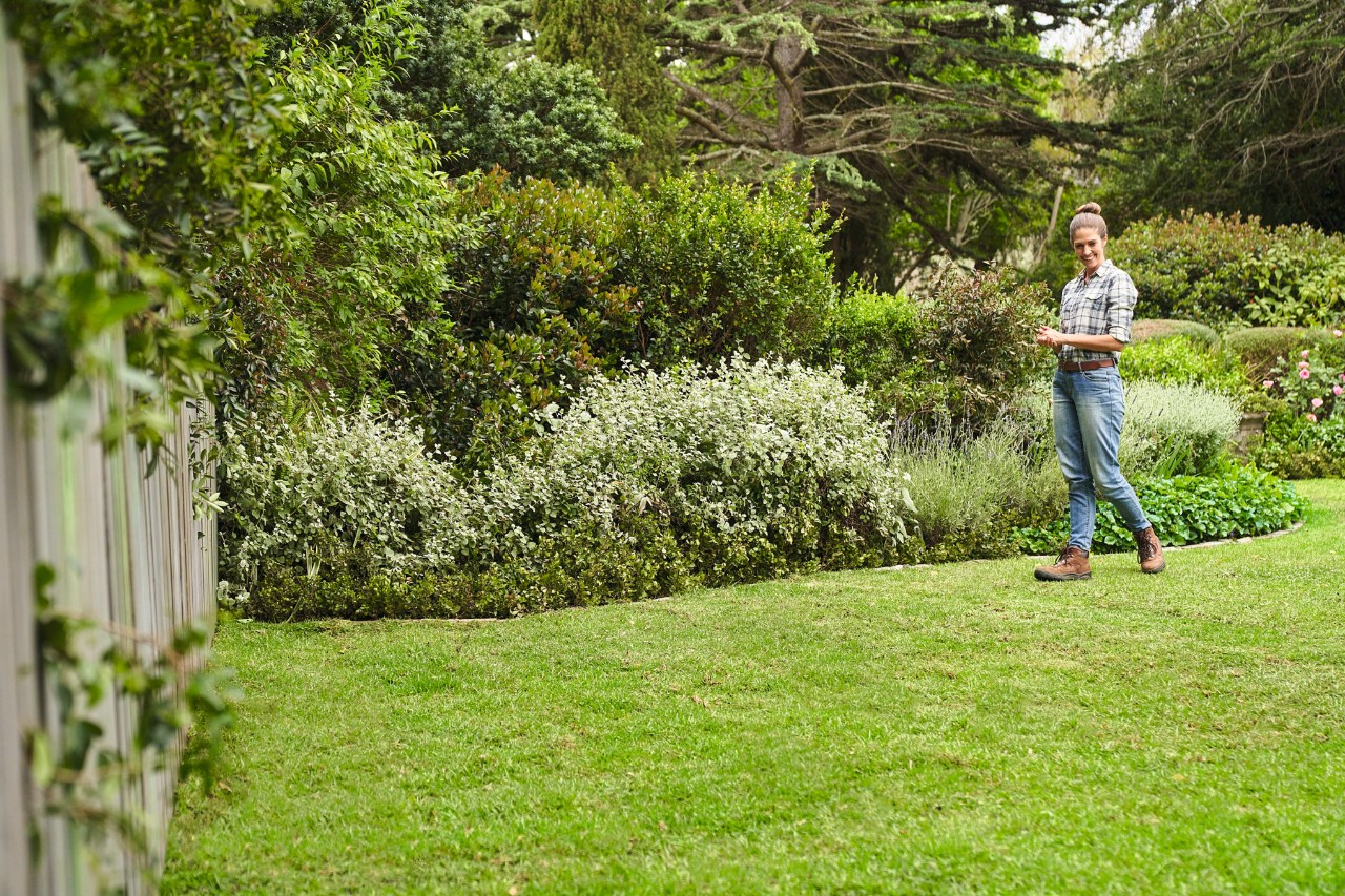 Une femme marche sur le gazon qui vient d’être installé dans son grand jardin