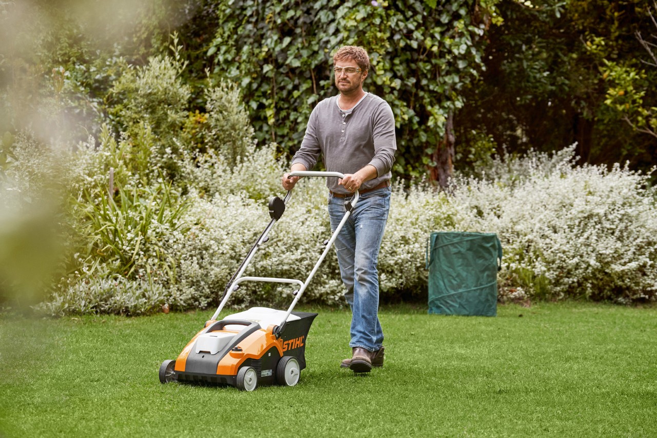 Un homme scarifie sa pelouse avec un scarificateur à batterie RLA 240 STIHL