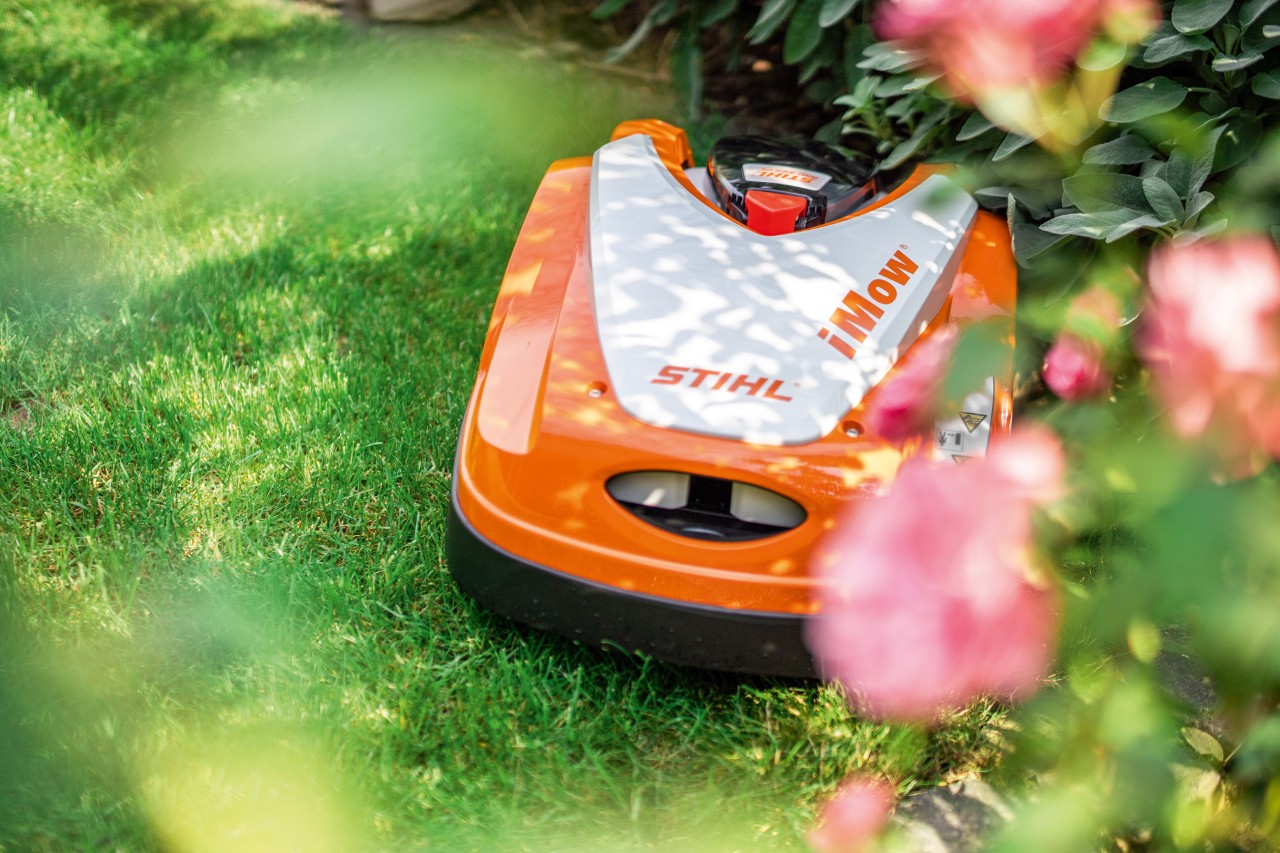 Robot de tonte iMOW de STIHL en train de tondre la pelouse de manière autonome dans un jardin.