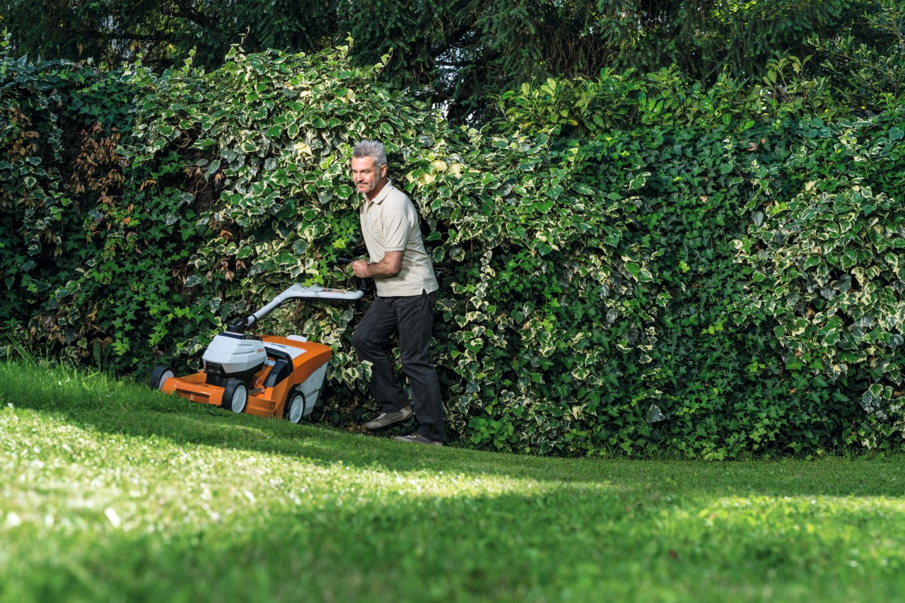 Un homme en train de tondre en pente avec une tondeuse à gazon à batterie STIHL&nbsp;RMA&nbsp;448&nbsp;TC  
