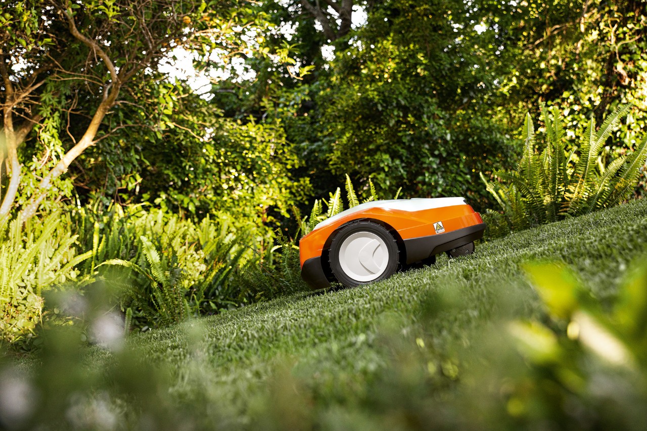 Une tondeuse robot iMOW® STIHL&nbsp;RMI&nbsp;522 en train de tondre une pelouse en pente