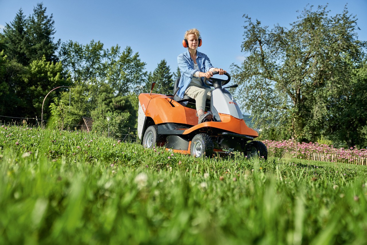 Une femme en train de tondre en pente avec une tondeuse à gazon autoportée STIHL&nbsp;RT&nbsp;4082 