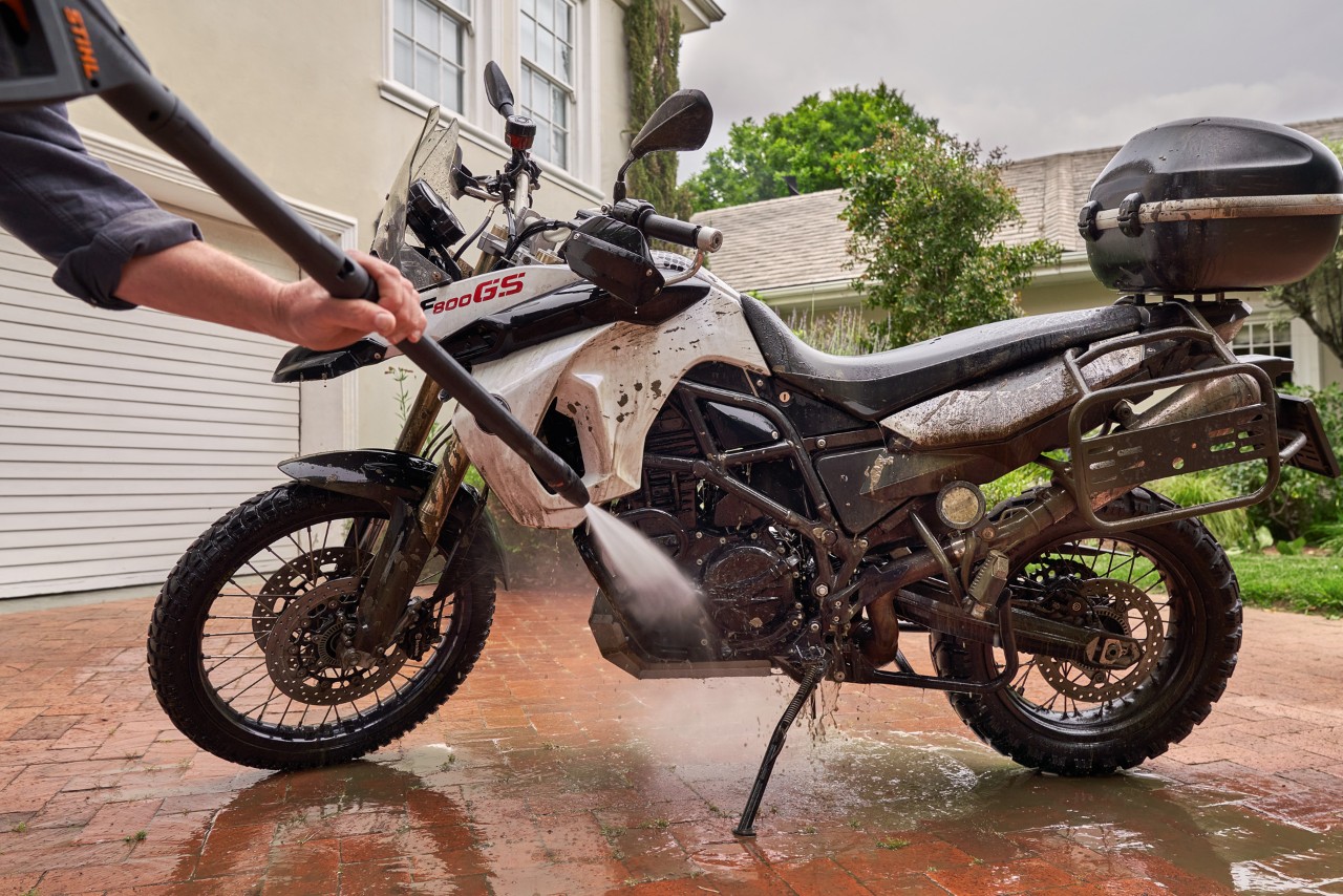 Moto sur une allée devant une maison blanche, nettoyée avec un nettoyeur haute pression STIHL RE 130 Plus