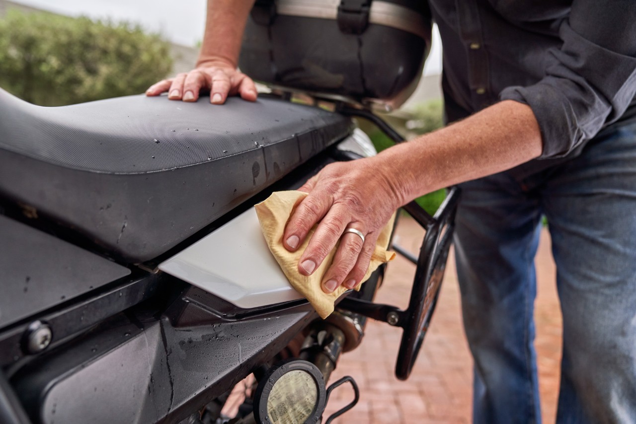 Gros plan sur de la cire appliquée avec un chiffon doux sur une surface peinte de la moto 