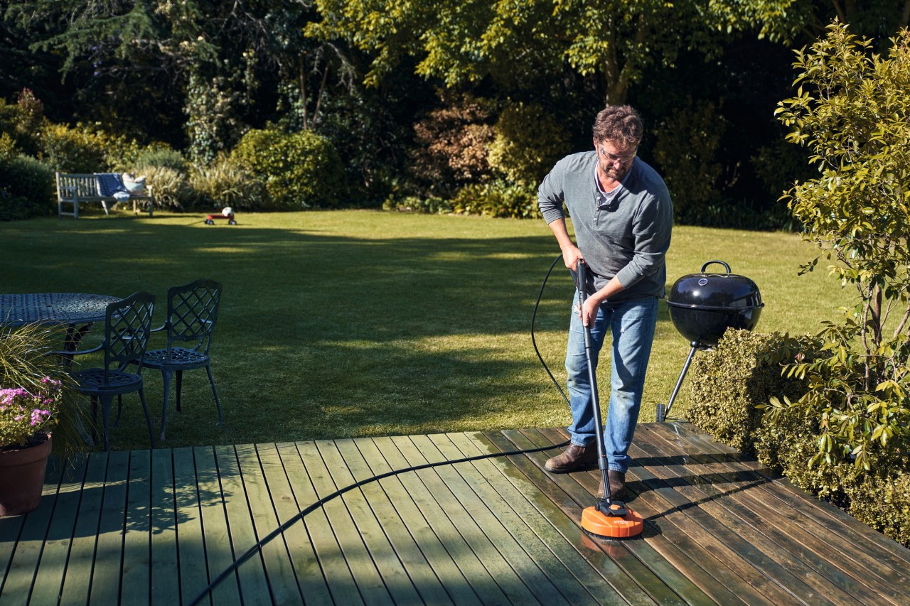 Un homme est en train de nettoyer la terrasse avec un nettoyeur de surface STIHL RA 82