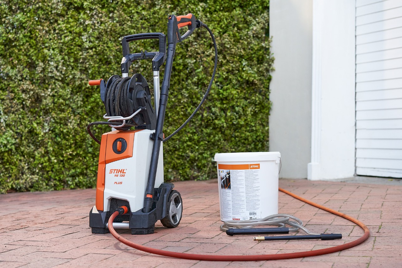 Nettoyeur haute pression STIHL RE 130 PLUS et abrasif de sablage SB 90 pour un sablage humide devant un garage 