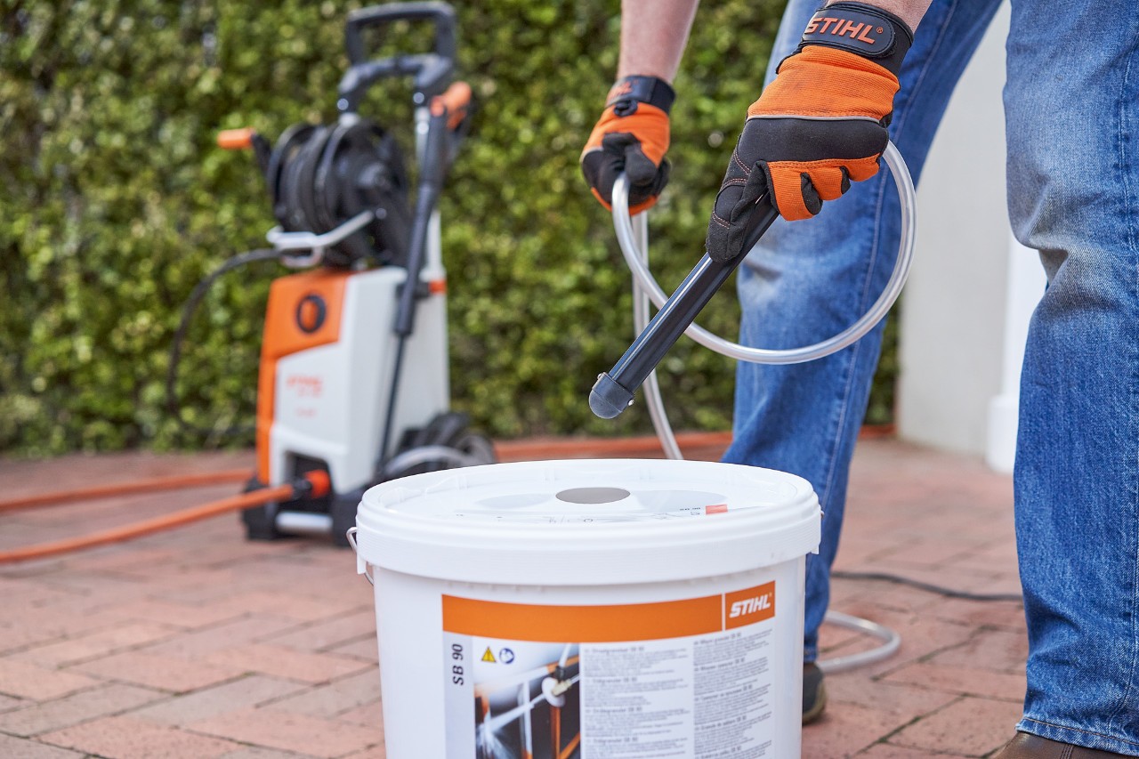 Un homme portant des gants de protection en utilisant l’abrasif de sablage STIHL SB 90 pour réaliser un sablage humide 
