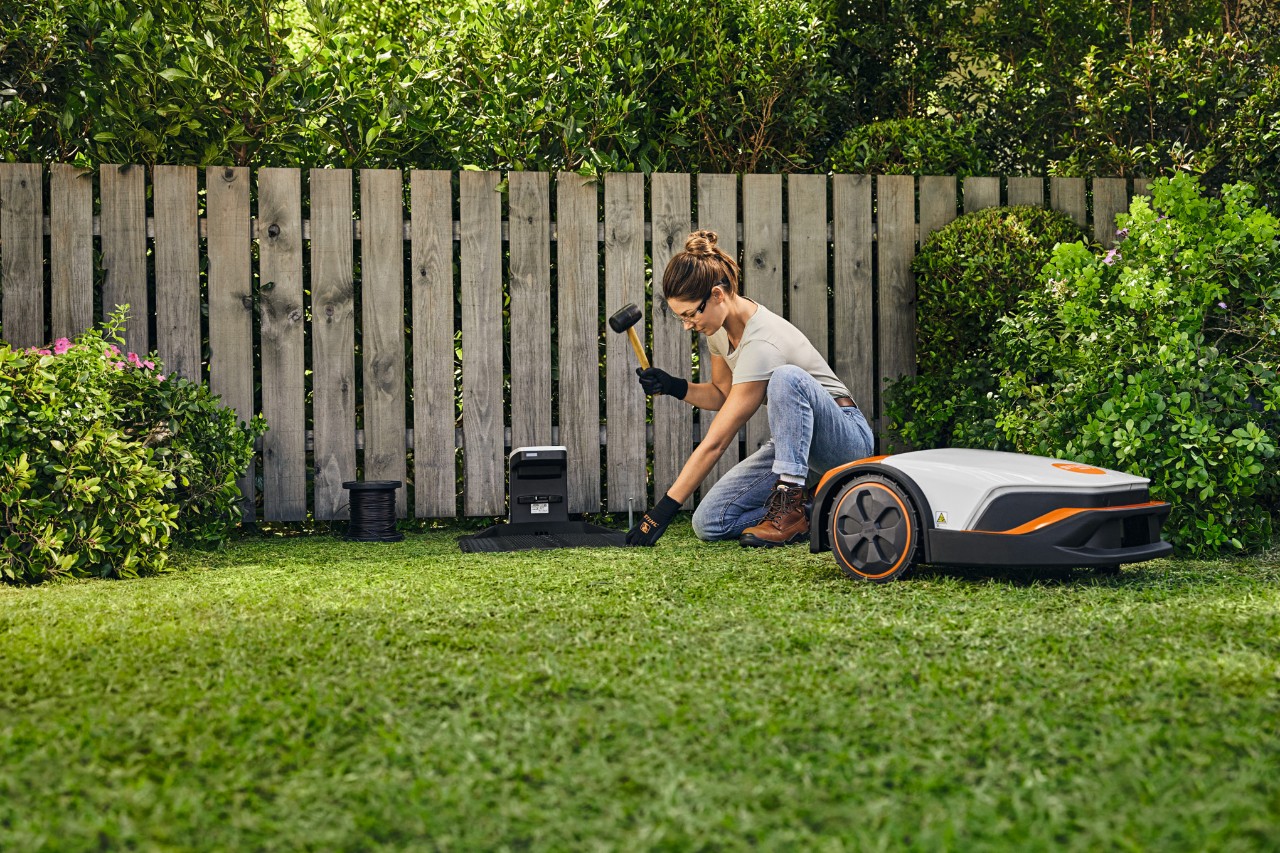 Une femme installe sa tondeuse robot iMOW