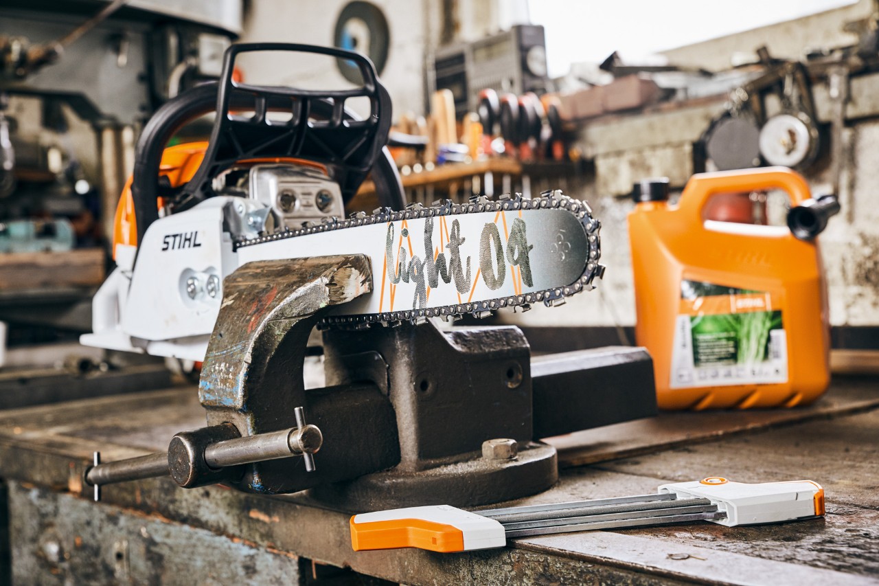 Tronçonneuse thermique MS 261 C-M de STIHL avec guide Light&nbsp;04 à côté du mélange de carburant STIHL MotoMix avant l’affûtage