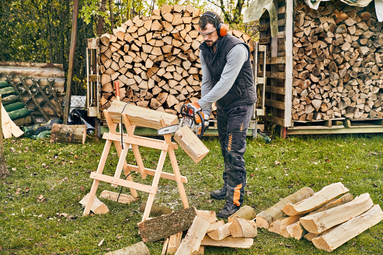 Les bûches d'un mètre de long sont raccourcies en bois de chauffage sur un chevalet avec une tronçonneuse STIHL MS 180