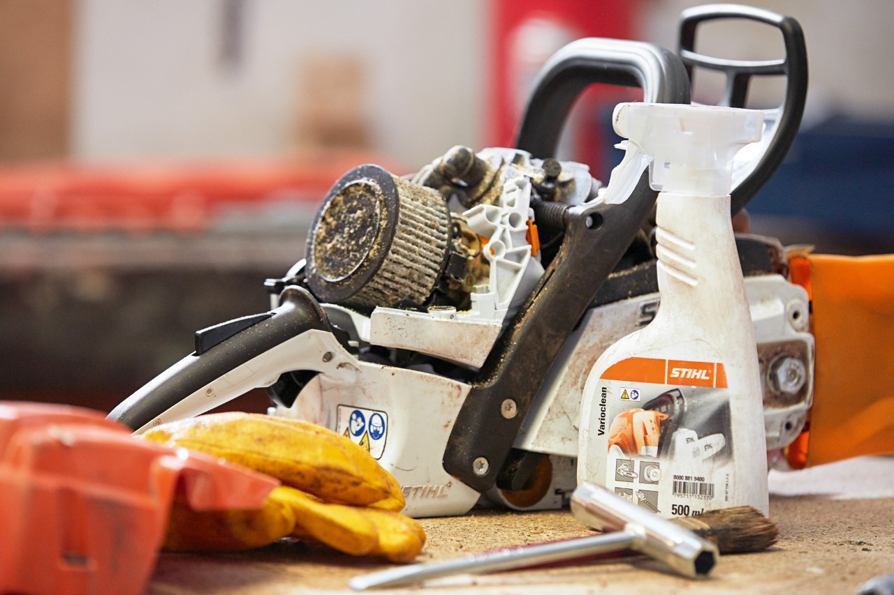 Nettoyant spécial pour la saleté organique ‘Varioclean STIHL’ devant une tronçonneuse STIHL sur un établi