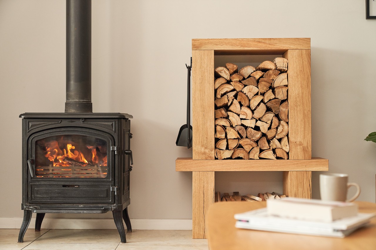 Meuble de rangement pour stockage bois chauffage intérieur à côté d’une cheminée allumée