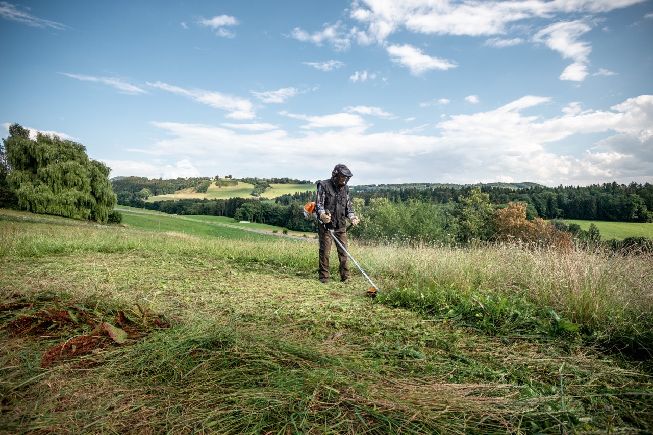 Une personne débroussaille une grande surface plane avec une débroussailleuse thermique STIHL FS 230