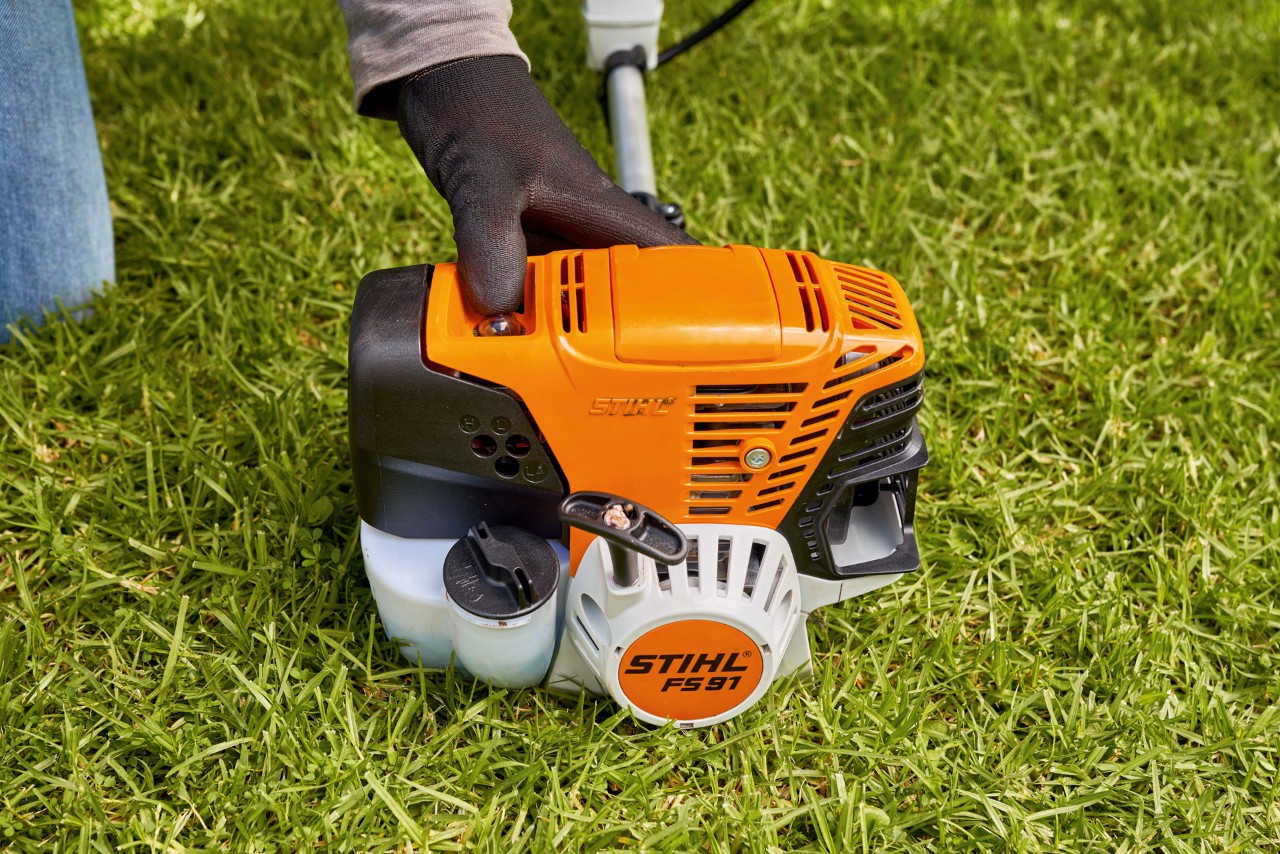 Un homme appuyant sur la pompe à carburant de la débroussailleuse à essence STIHL&nbsp;FS&nbsp;91 pour la démarrer