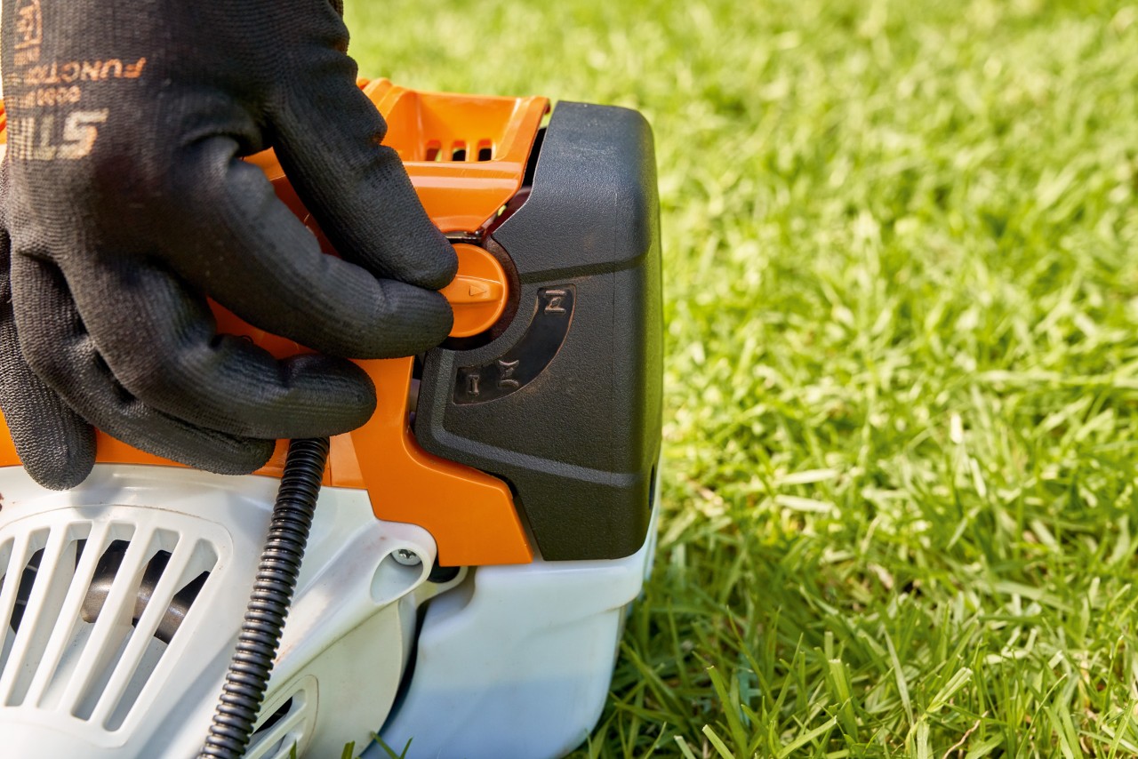 Un homme réglant le levier de la pompe à carburant de la débroussailleuse à essence STIHL&nbsp;FS&nbsp;91 pour la démarrer